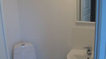 A small, white bathroom with a toilet and a sink.