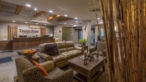 A lobby with a reception desk, leather sofas, a coffee table, and a decorative bamboo structure. - Timber Ridge Inn and Suites (Fox Creek)