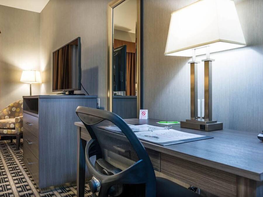 Une chambre d’hôtel équipée d’un bureau, d’une chaise, d’une télévision, d’une lampe et d’un miroir.