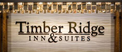 A sign for Timber Ridge Inn & Suites with a textured background and illuminated letters.