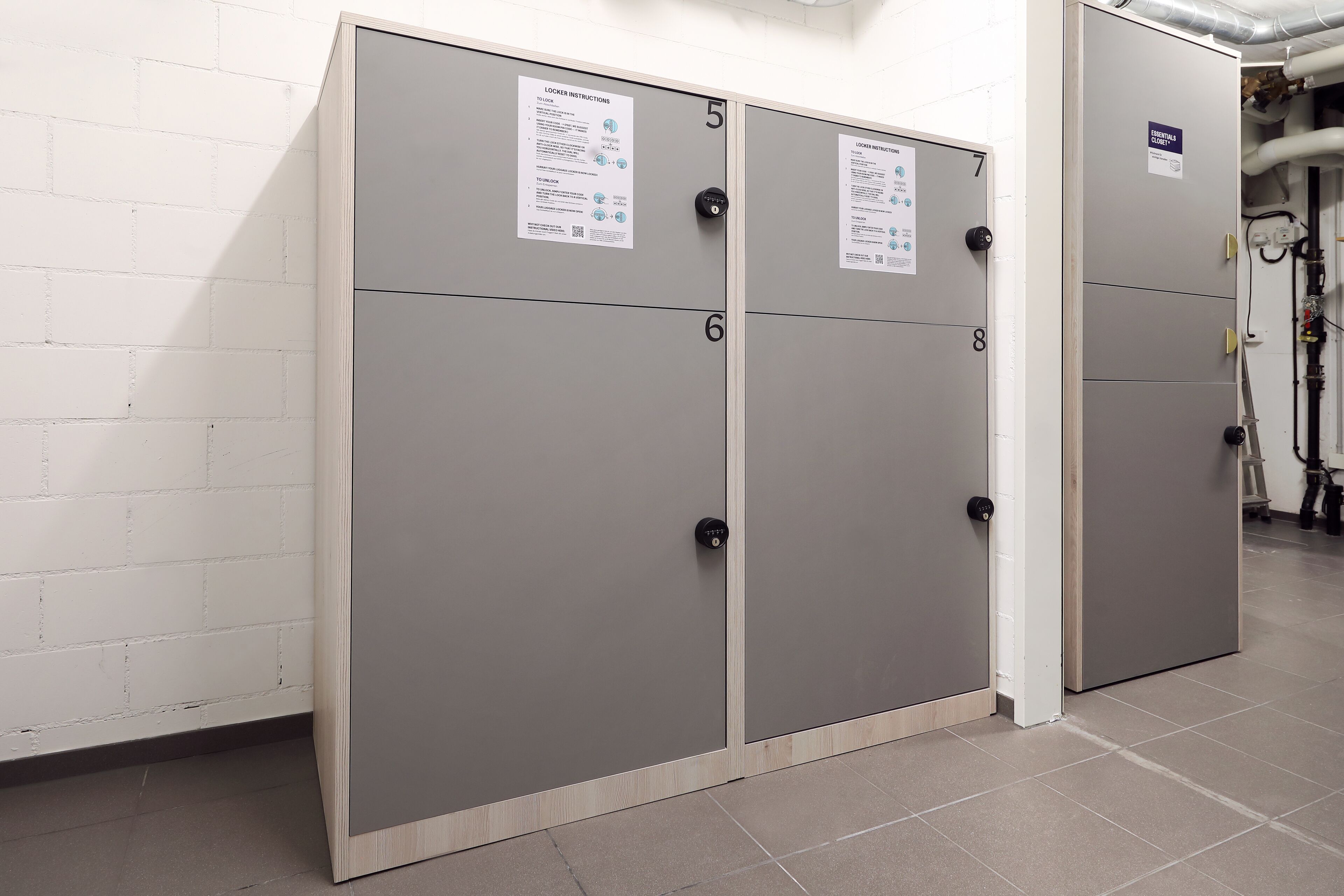 Una hilera de taquillas grises con puertas numeradas y carteles instructivos.