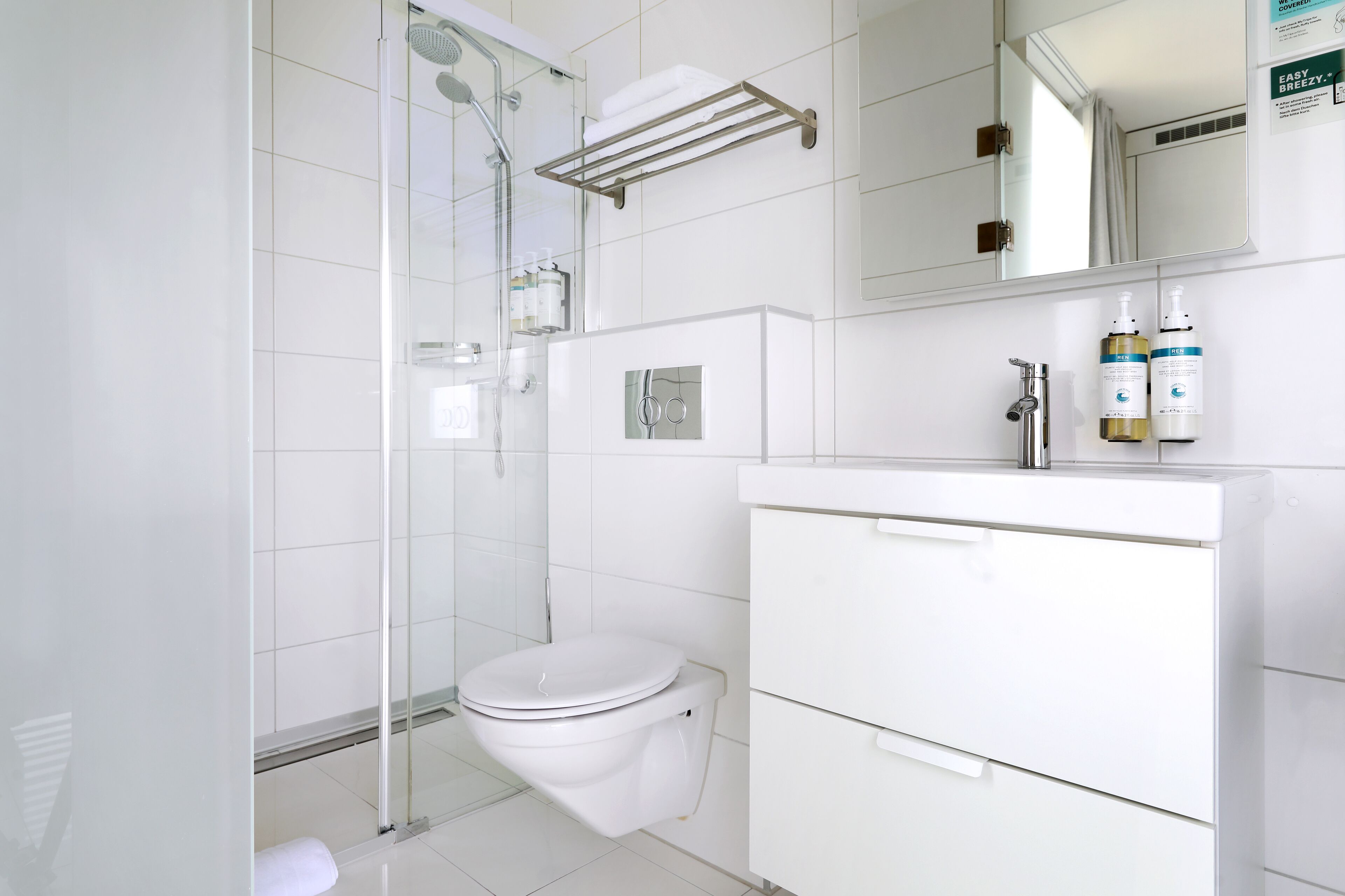 A modern bathroom with a glass-enclosed shower, a white toilet, and a vanity with storage drawers.