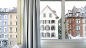 A view through a window of a building with multiple stories, featuring a mix of architectural styles and a variety of window designs. - Numa Zurich Turi (Zürich)
