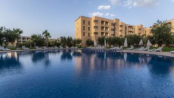 Una piscina al aire libre, sombrillas, sillones reclinables de piscina