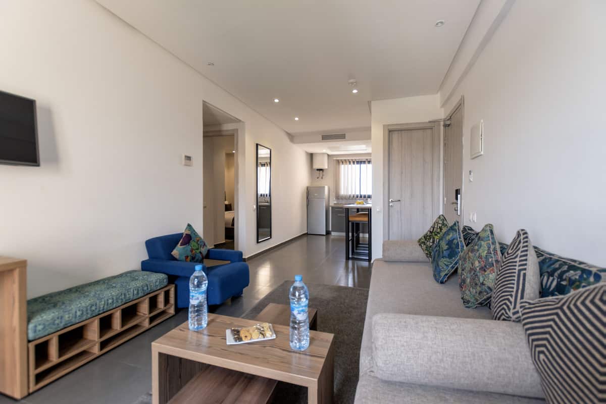 A modern living room with a sofa, a coffee table, and a bench. There are two water bottles on the table.