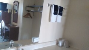 Un baño con lavamanos, espejo, toallero y una toalla colgada.