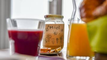 Un tarro de vidrio con una etiqueta que dice "Miel" y un vaso de jugo de naranja sobre una mesa.