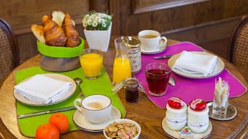 A breakfast table with croissants, orange juice, coffee, tea, and yogurt parfaits.