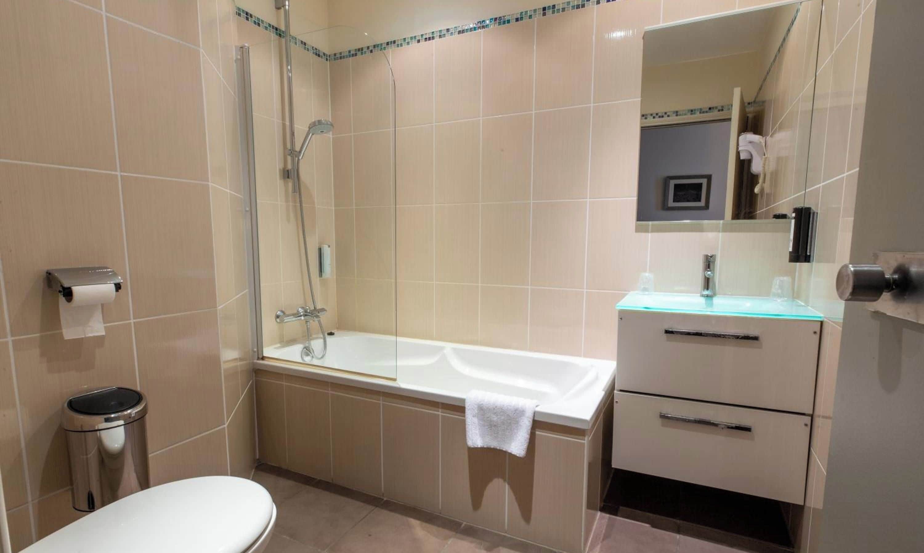 Ein Badezimmer mit Toilette, einer Glasdusche, einer Badewanne und einem Waschtisch mit Spiegel.