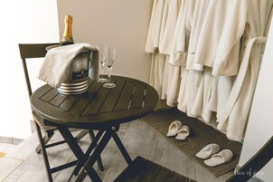 Una mesa con una botella de champán, dos copas y un par de pantuflas.
