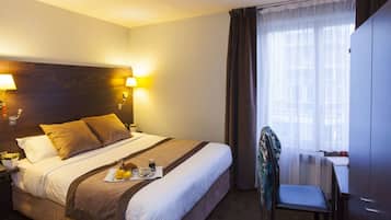 A hotel room with a large bed, bedside lamps, a desk, and a chair.