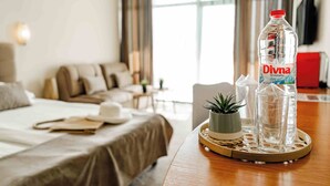 A hotel room with a bed, a dining table with a tray of water bottles, a small plant, and a potted plant. - Palm Beach Hotel- All Inclusive (Golden Sands)