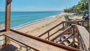 A wooden deck overlooking a beach with a clear view of the ocean and palm trees. - Tamboo Beside the Pointe (Rincon)