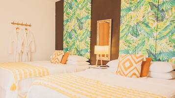 A hotel room with two beds, a mirror, and a tropical leaf-patterned wall.