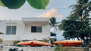 A building with a sign reading "Cayucos RINCON, PUERTO RICO" and outdoor umbrellas. - Tamboo Beside the Pointe (Rincon)