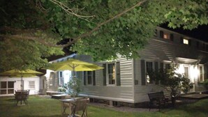 A two-story house with a patio area featuring a table and chairs under a yellow umbrella.