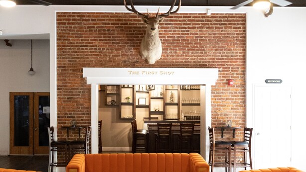 Een modern interieur met een bakstenen muur, een kroonluchter, oranje banken en een houten salontafel.