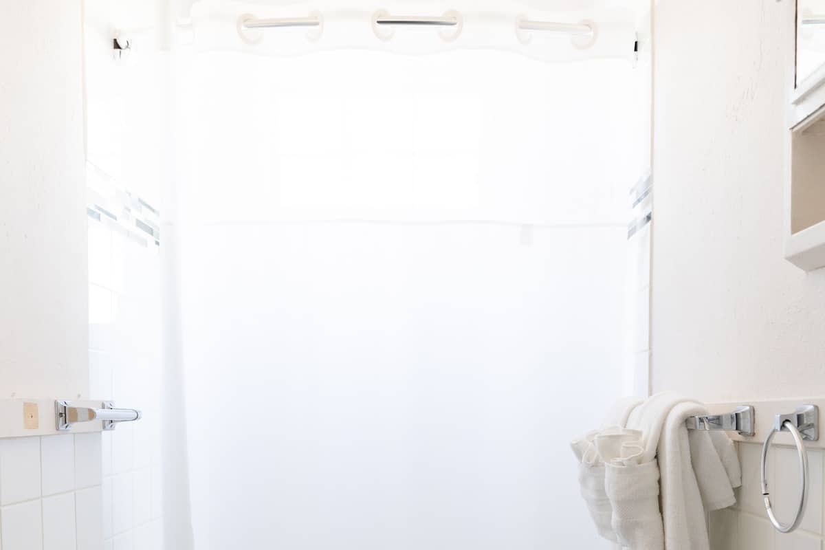 A small, white bathroom with a toilet, sink, and shower curtain.