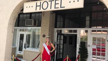 A hotel entrance with a sign reading "HUNTER ARMS HOTEL" and a red carpet leading to the door.