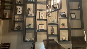 Een bar met planken waarop flessen, glazen en decoratieve objecten staan.