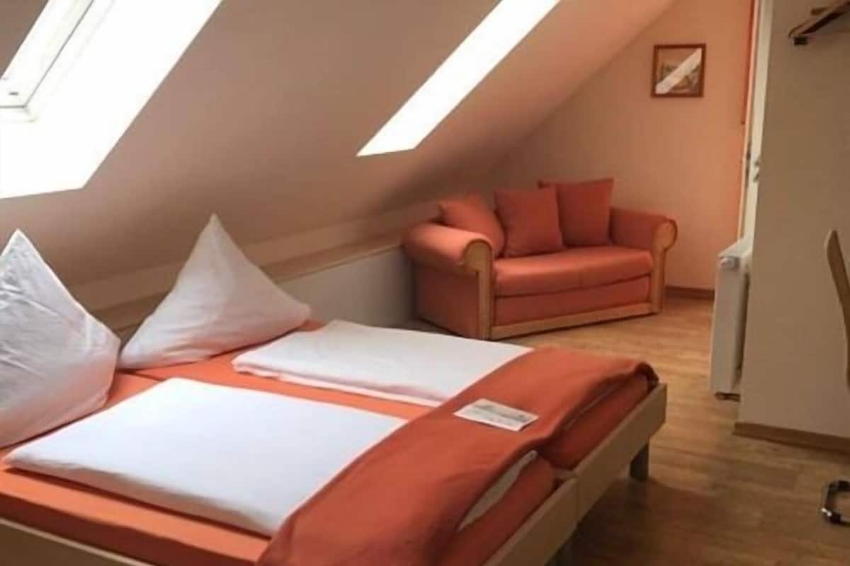 Een slaapkamer met een bed, een bank en een raam.