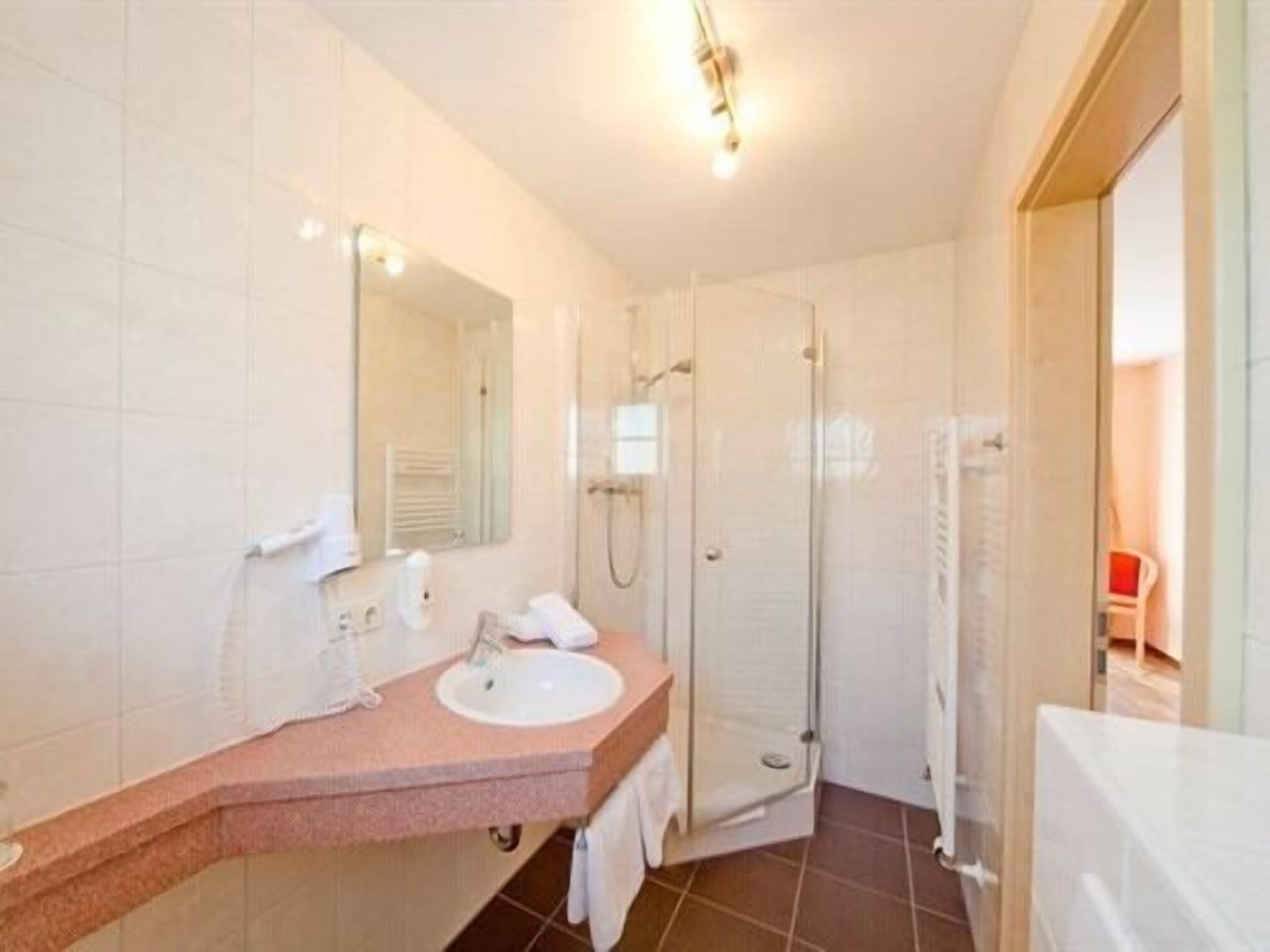 Een badkamer met een wastafel, spiegel en douche.