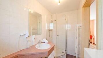 Een badkamer met een wastafel, spiegel en douche.