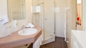 Une salle de bain moderne avec un lavabo blanc, une douche à parois de verre et un grand miroir.