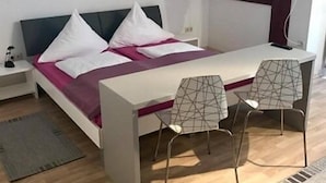 Une chambre à coucher moderne avec un lit, des tables de chevet, un bureau et deux chaises.