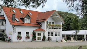 Un bâtiment à deux étages, doté d’un toit recouvert de tuiles rouges, d’un balcon orné de plantes en pot et d’une enseigne indiquant « Landgasthof Feihl ».