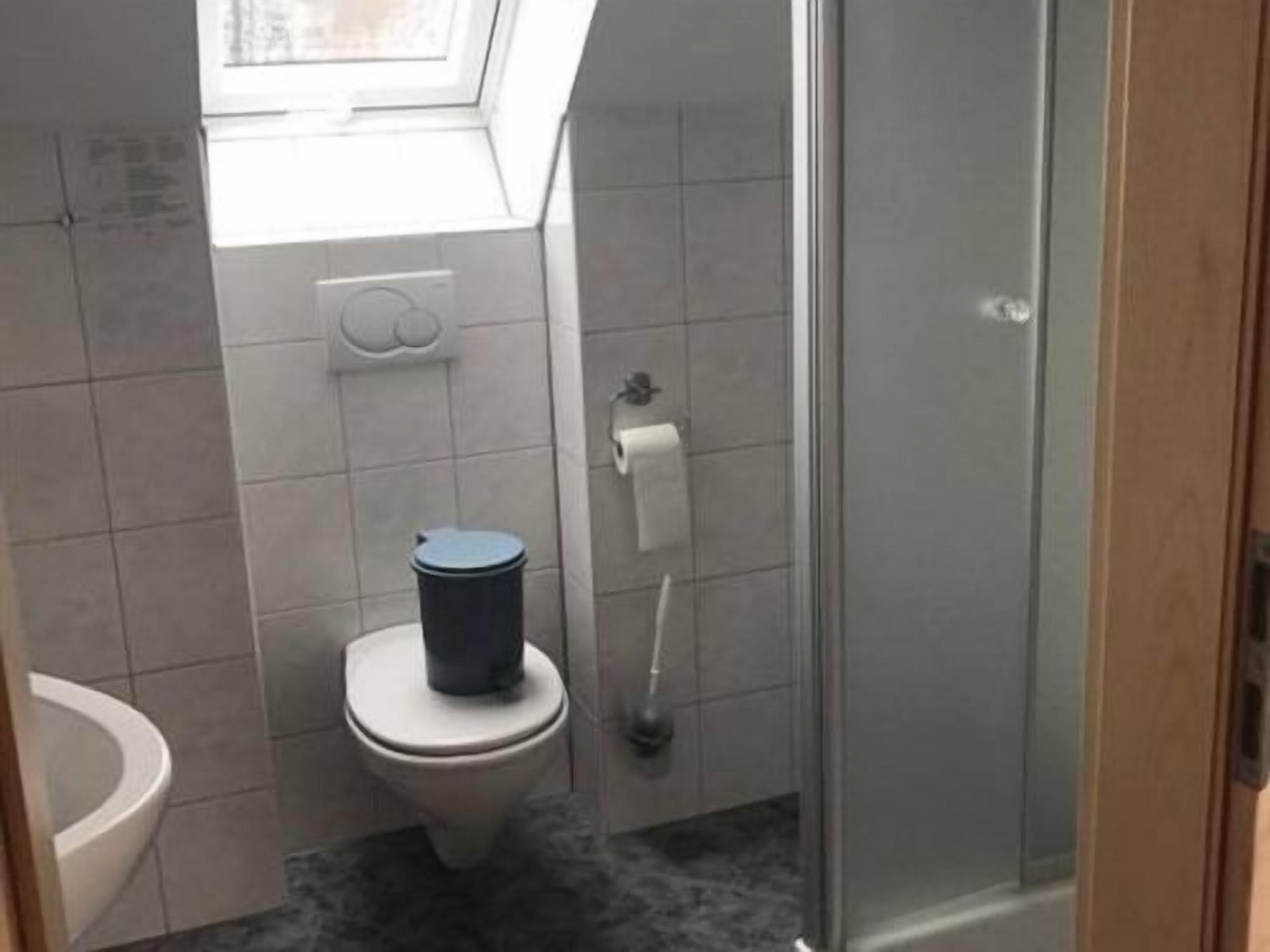 Un baño pequeño con inodoro, secador de manos y cabina de ducha de vidrio.