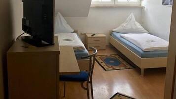 Una habitación pequeña y poco amueblada con escritorio, silla, cama y ventana.