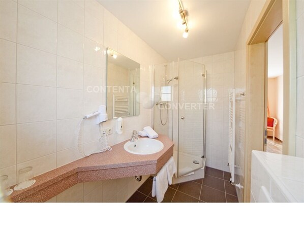 A modern bathroom with a glass shower enclosure, a white sink, and a vanity with a mirror. - Landgasthof Feihl (Velburg)