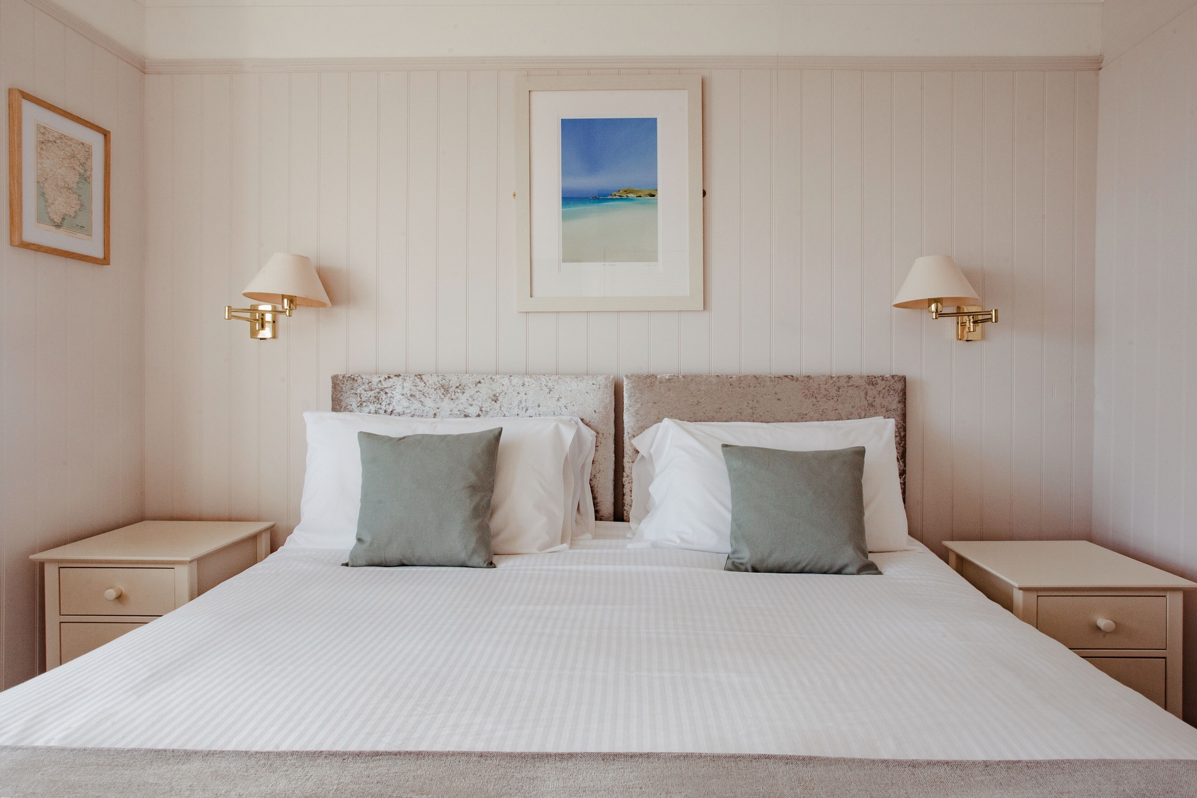 A neatly arranged bedroom with a large bed, two nightstands, and wall-mounted lamps.