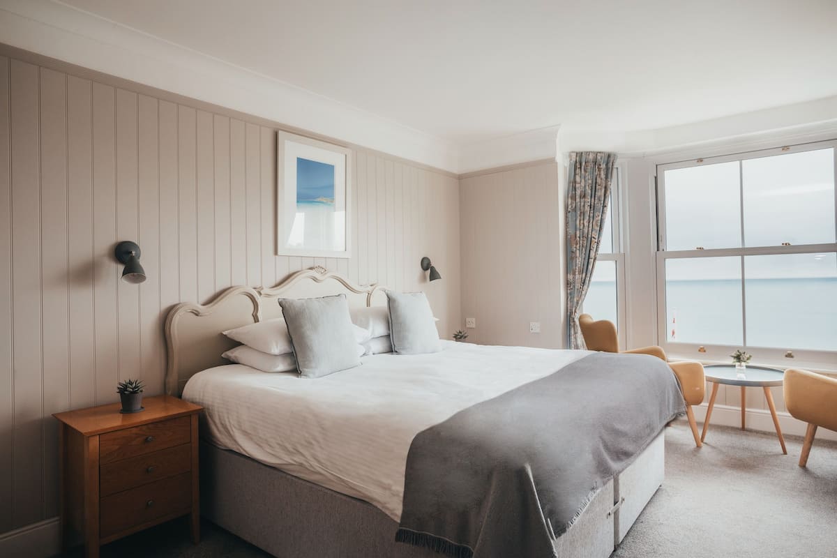 A bedroom with a bed, bedside tables, a small table, and a chair.