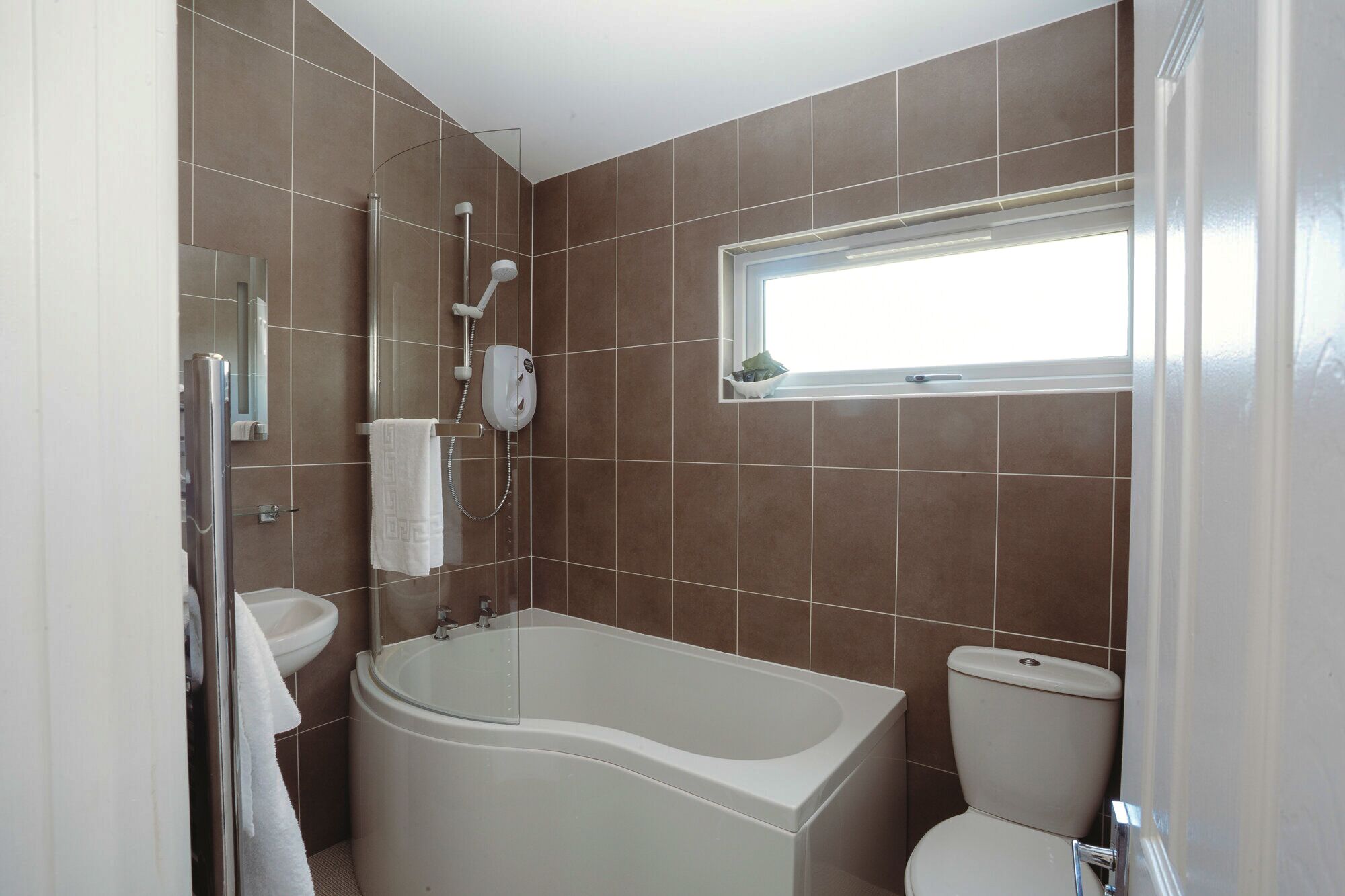 A bathroom with a bathtub, toilet, and a window.