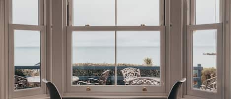 A bay window with a view of a patio area, including chairs and a table.
