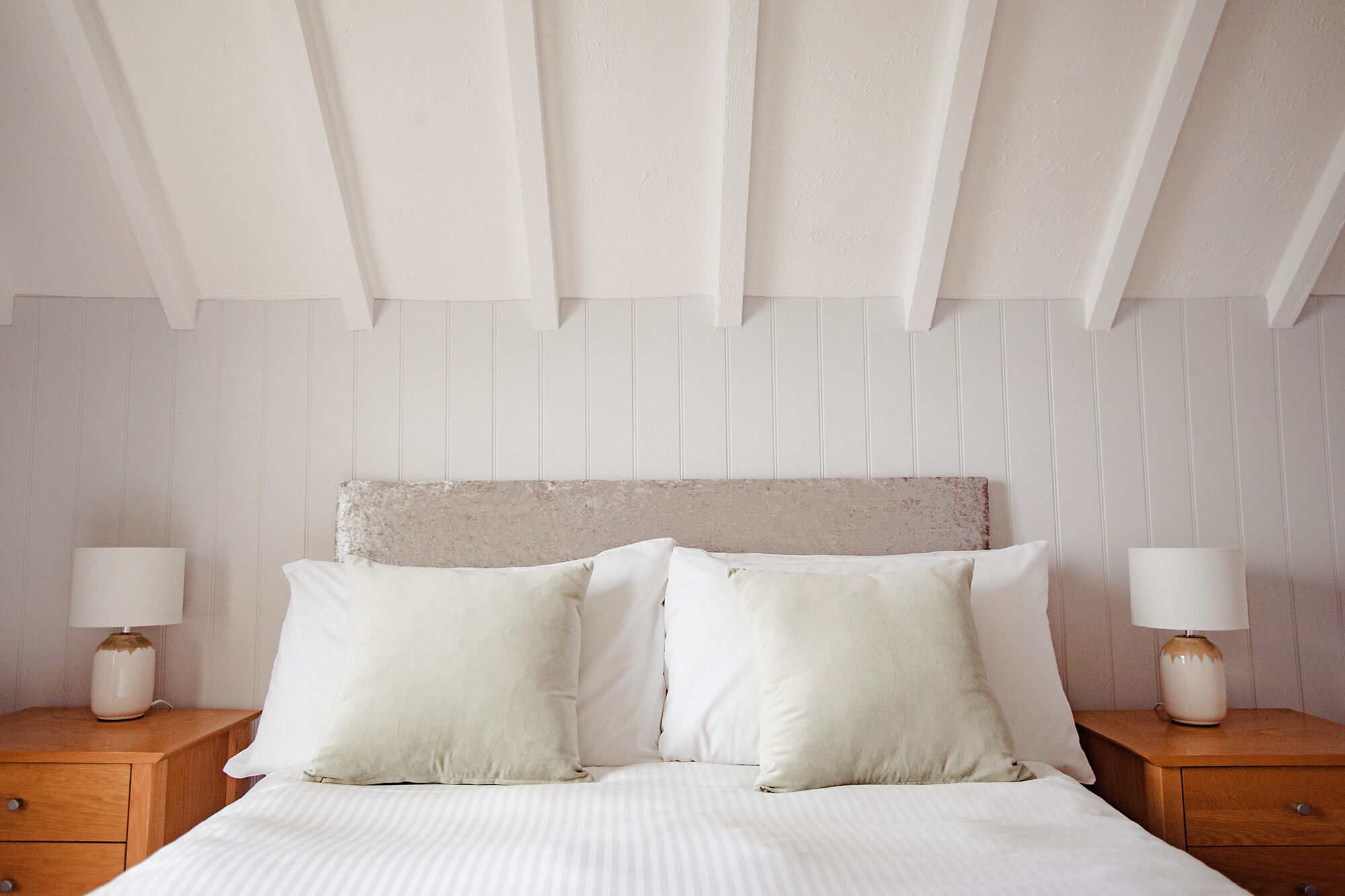 A bedroom with a bed, two nightstands, and a headboard.