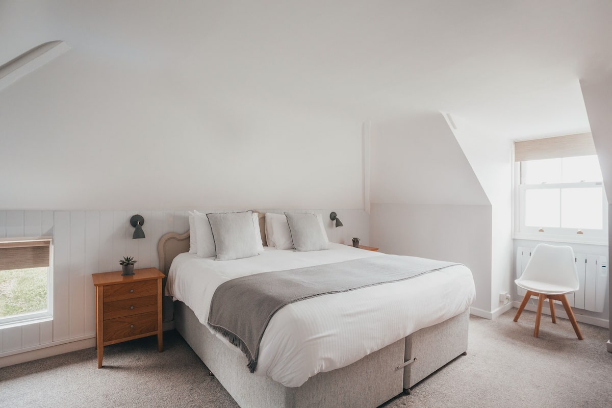 A bedroom with a bed, nightstands, a chair, and a window.