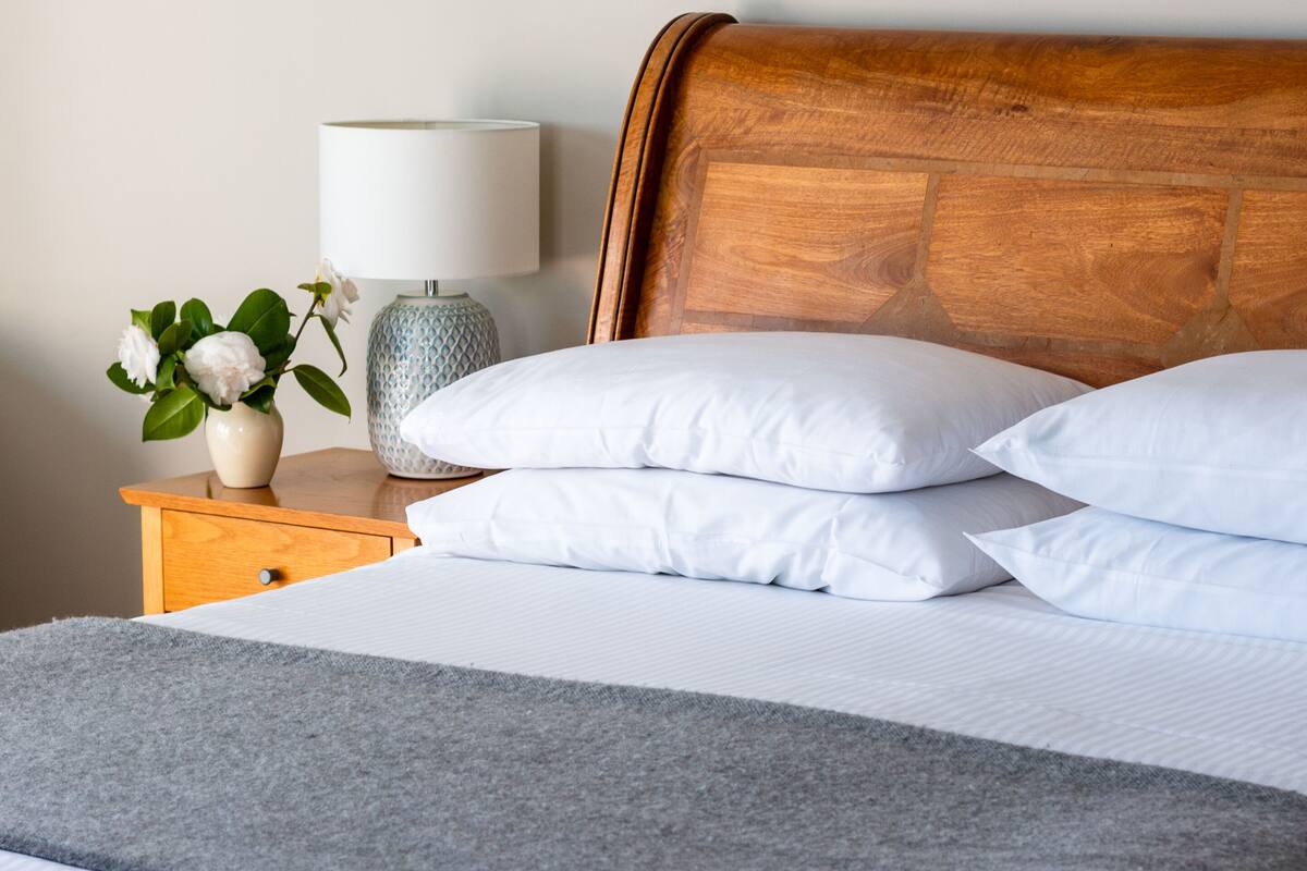 A neatly made bed with white pillows and a grey throw blanket.