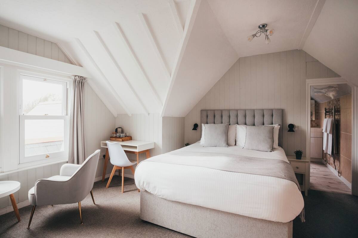 A bedroom with a large bed, a desk, and a chair.