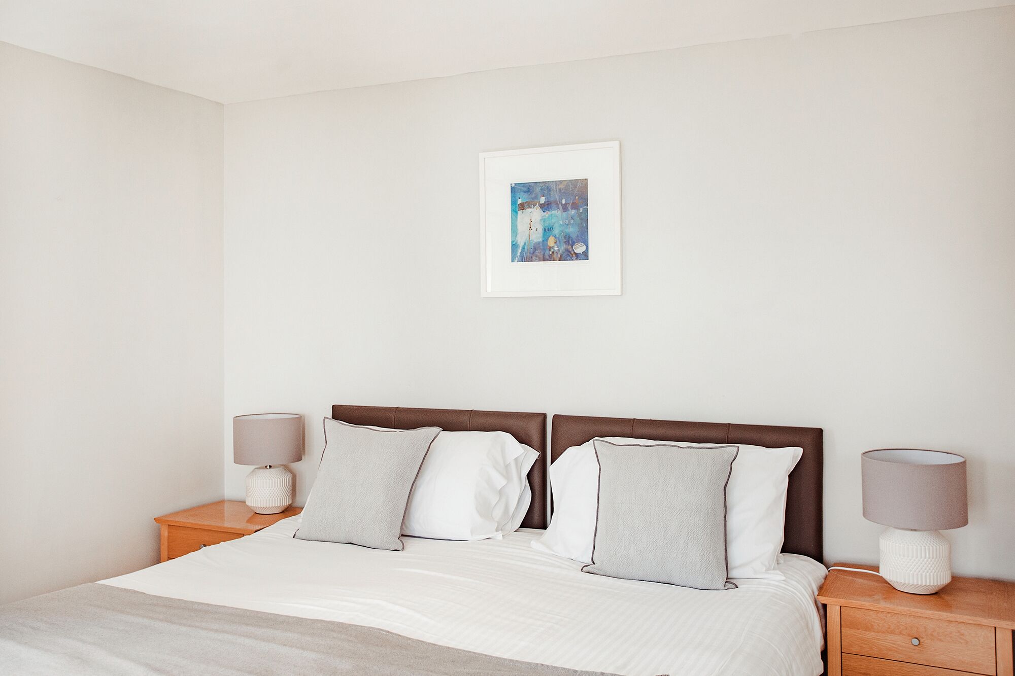 A neatly arranged bedroom with a bed, two bedside tables, and a single wall-mounted picture.