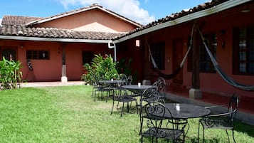 A courtyard with outdoor seating, a hammock, and a building with a tiled roof.