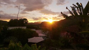 A sunset over a hilly landscape with a view of a residential area and some vegetation. - La Casa de Cafe (Copan Ruinas)
