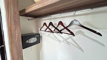 A room with a wooden shelf, a hanging coat rack, and a safe.