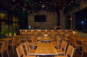 Un restaurante con mesas y sillas de madera, una pared de piedra y luces colgantes.
