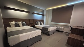 Una habitación de hotel moderna con dos camas, un escritorio y un ventanal grande.