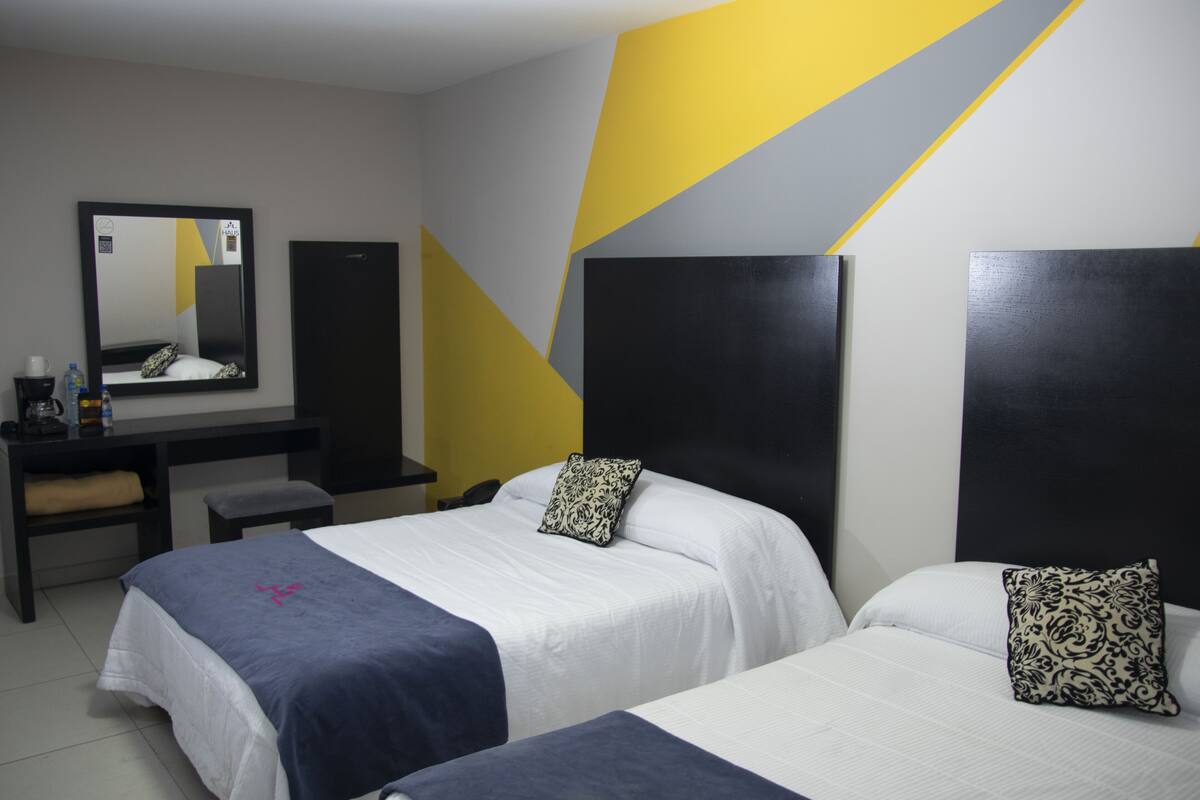 Ein Hotelzimmer mit zwei Betten, einem Schreibtisch und einem Spiegel.