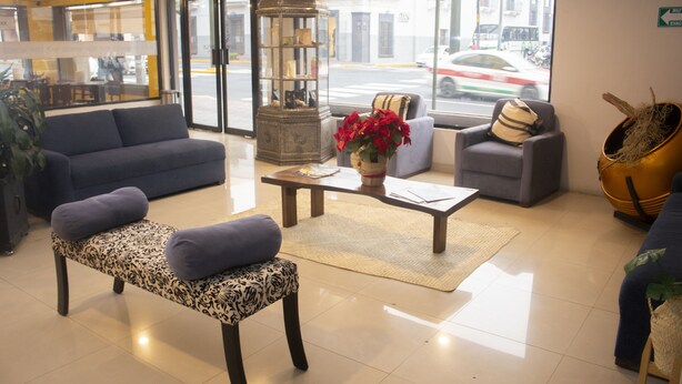 Un moderno vestíbulo de hotel con sofá, sillón y una lámpara decorativa.