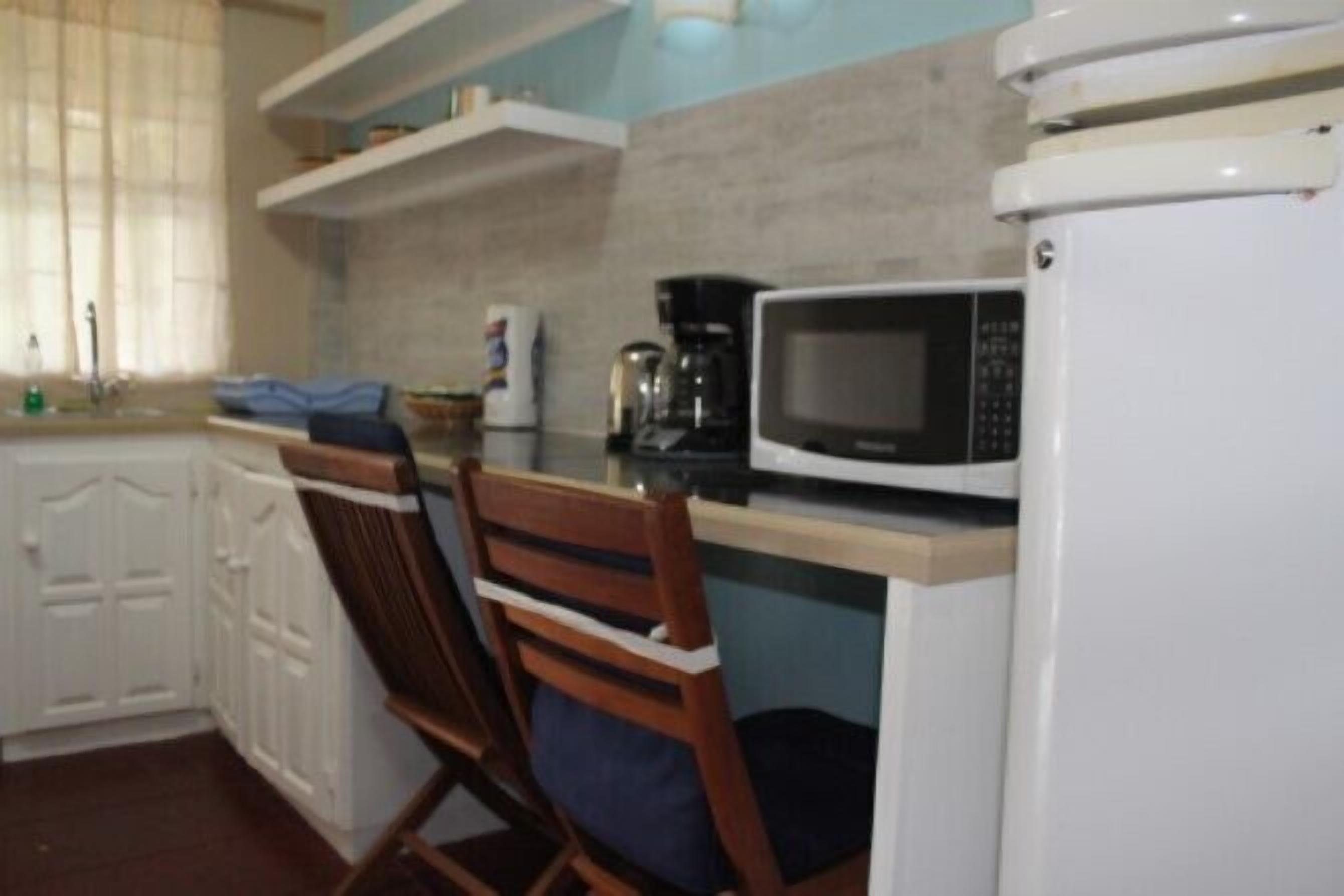 A compact kitchen with white cabinets, a microwave, and a coffee maker.